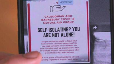 A volunteer group to help people self-isolating shown a mobile phone