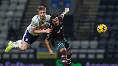 Preston North End's Liam Lindsay (L) heads the ball under pressure from Swansea City's Adam Idah 