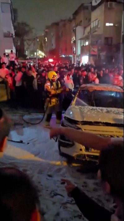Fireman tackles a burning car as a crew stand around him