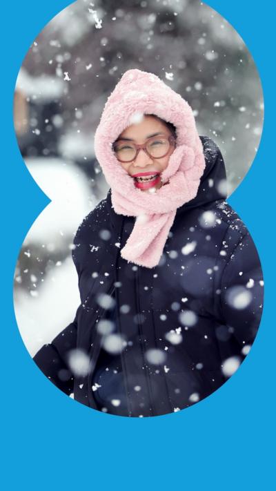A woman wearing a pink hood and a blue jacket smiles in the snow, in Alford in Scotland, on 6 January 2026