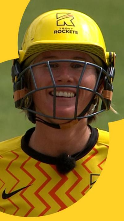 Beth Mooney smiling while talking to the commentators through her microphone on-field
