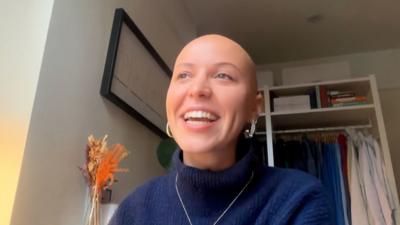 An image of Jasmine Mitchell smiling with a blue jumper on and silver jewellery