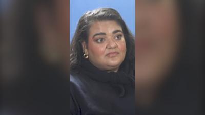 Billie Bhatia has long dark hair and is wearing a dark top.