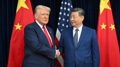 Donald Trump and Xi Jinping shake hands in front of American and Chinese flags