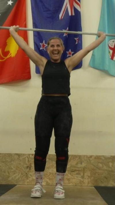 A woman in black gear weightlifting