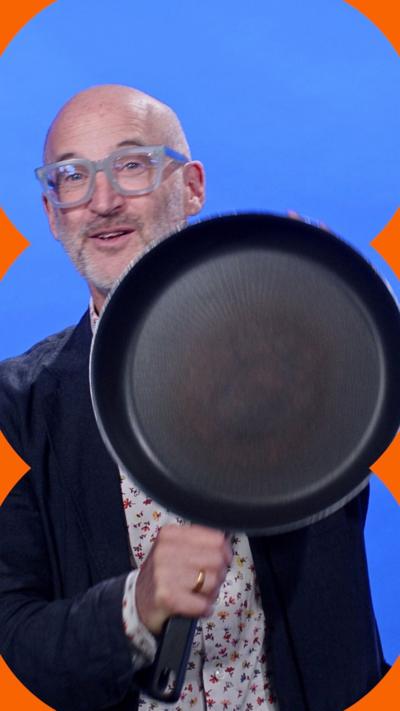 Scientist Mark Miodownik is standing against a blue background, holding a frying pan to camera