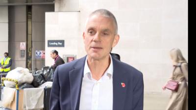 Tim Davie wearing a navy blue suit jacket and a white shirt.