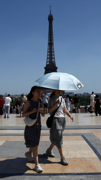 People shelter under an umbrella near the Eiffel Tower 