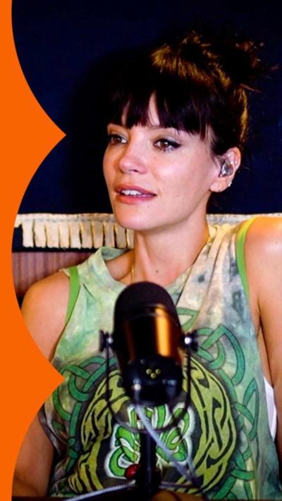 Lily Allen sits behind a microphone - she wears a green patterned sleeveless top and has a dark fringe