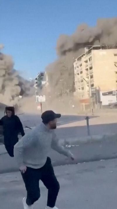 Two people running from an explosion behind them