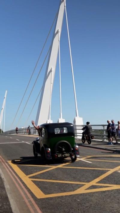 Vintage car going past people on the new bridge