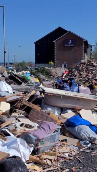 A view of a heap of rubbish left in Glastonbury. There is a bathtub and planks of wood.