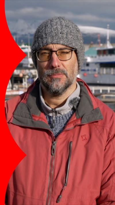 Man in grey beanie, glasses and red coat