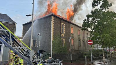 Flames are visible reaching up into the sky of the Bethany English Calvinistic Methodist Chapel on Station Road in Port Talbot. Firefighters are spraying water at it. 