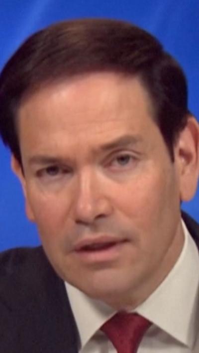 A man with short black hair and mouth agape looks into the camera.