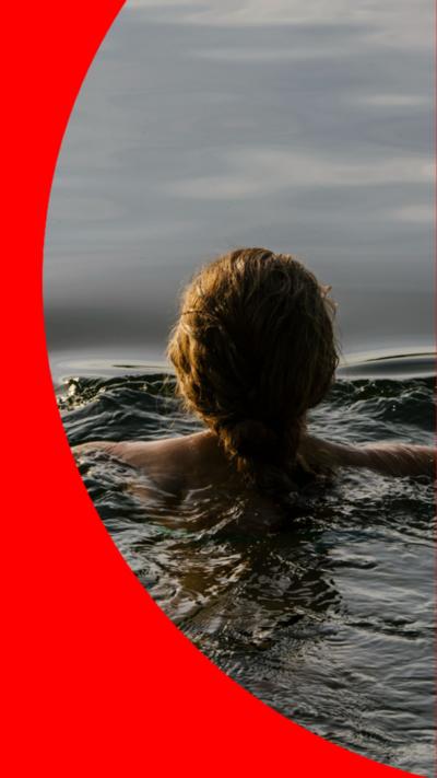 The back of a woman's head who is neck deep in water.