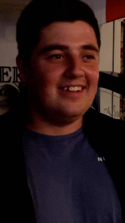 A young man smiles while stood in a pub