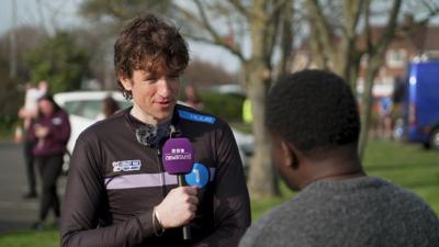 greg james holding a purple newsround microphone talking to De-Graft