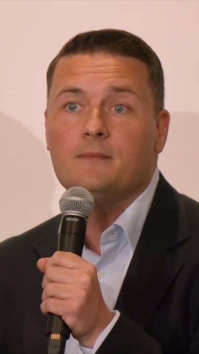 Wes Streeting holding a microphone up to his mouth 