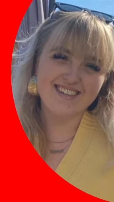 Woman in yellow top smiles looking directly to camera.