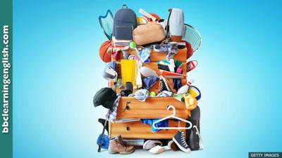 A very cluttered chest of drawers that's overflowing with a range of objects