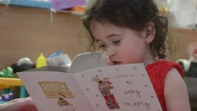 four-year-old Evie Green reading a Christmas card