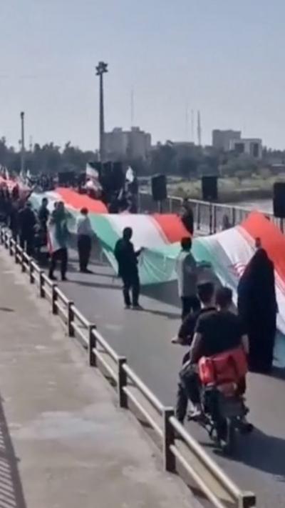 Human chain holding giant Iranian flag on bridge