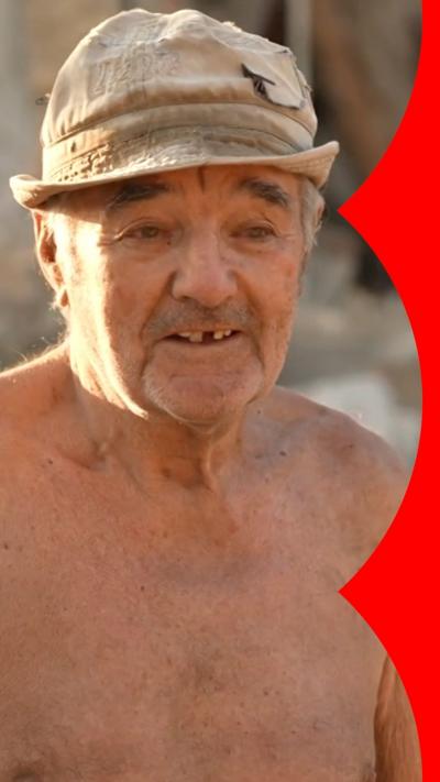 A shirtless elderly man wears a hat and speaks to the BBC after losing his home in Russian airstrikes