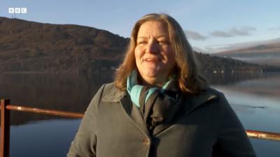 Fiona Fotheringham agus i na seasamh air beulaibh an loch agus là breagha ann. 