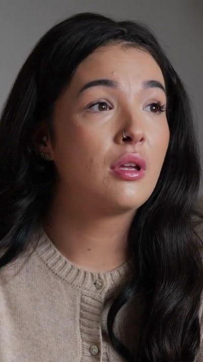 A woman with brown hair wearing a cream cardigan.