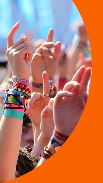 People’s arms up in a festival crowd, several people are wearing colourful festival wristbands