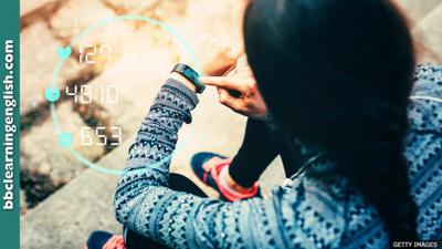 A woman sitting on some steps photographed from behind over her left shoulder. She is touching a fitness tracker on her wrist. The tracker displays a holographic circle containing her fitness stats including heart rate.