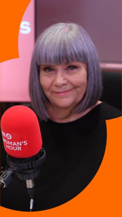 Dawn French wearing a black top, sat in a studio with a red mic in front of her.