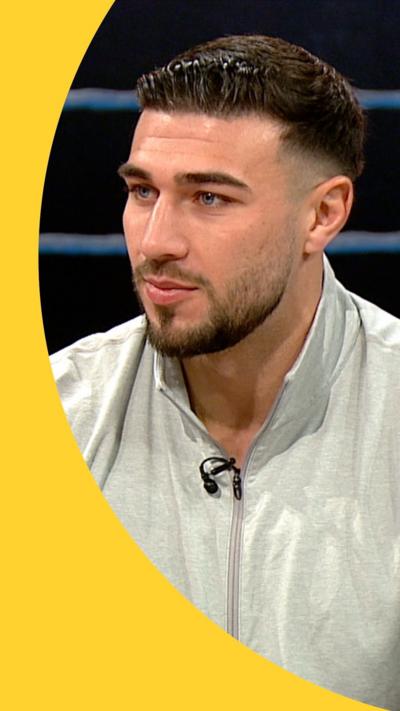 Tommy Fury sat down, looking away from the camera, wearing a light grey zip up track top.