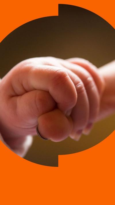 A baby's finger is holding the end of its mother's finger