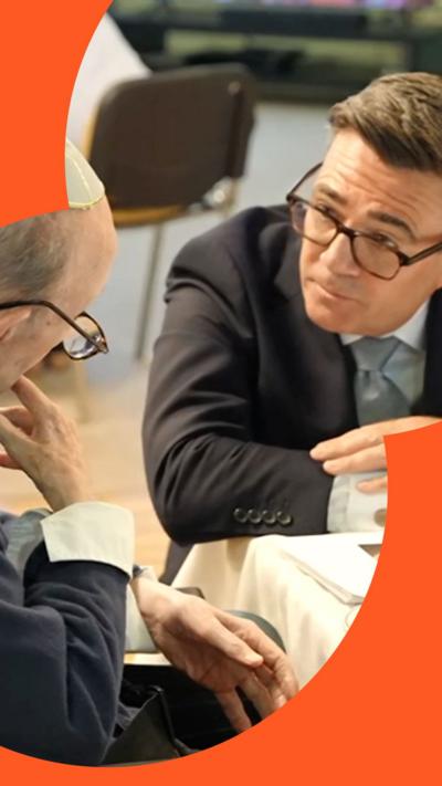 Younger man in suit listening attentively to an elderly man wearing a kippah