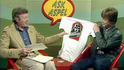 Mark Hamill holds up a Star Wars T-shirt which reads 'Happy Empire Day' on Ask Aspel.