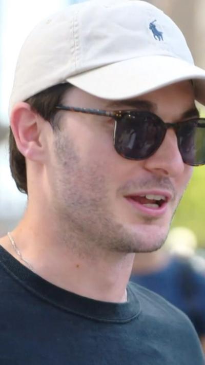 A man wearing a white hat and dark sunglasses.