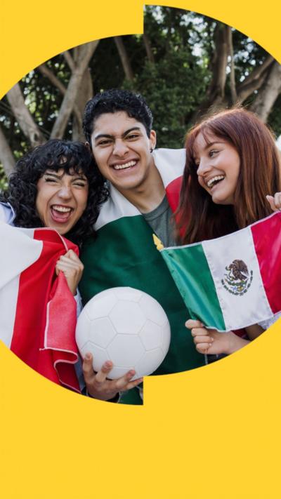 Three smiling football fans draped in Mexican flags. The one in the middle is holding a football.