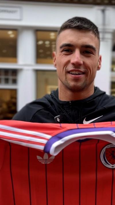 Man looking into camera holding up the new away jersey