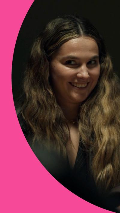 Young woman gives knowing smile to the side in a darkly lit room