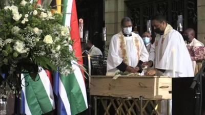 Coffin in front of South Africa flags