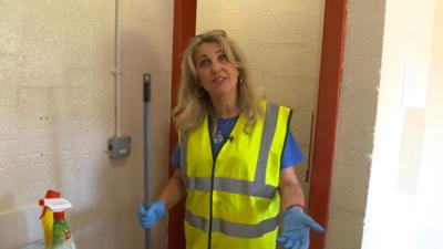 Volunteer standing with mop cleaning toilets