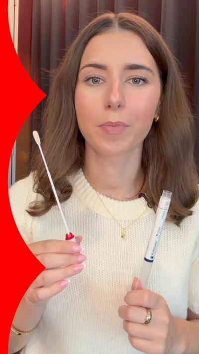 A woman holds up an HPV testing kit.