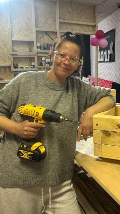 A woman wearing glasses and holding a drill