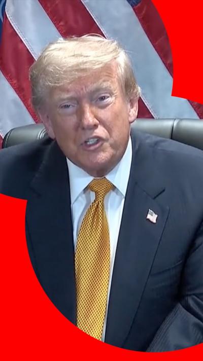 Presdident Donald Trump is wearing a white shirt, dark jacket and a gold patterned tie. He is wearing a badge of the US flag.