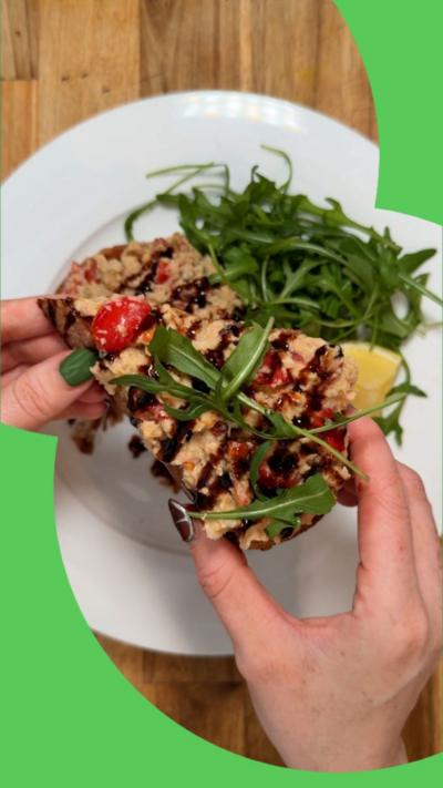 A bird's eye view of chickpea paste spread on bread and served with rocket leaves and a balsamic glaze.