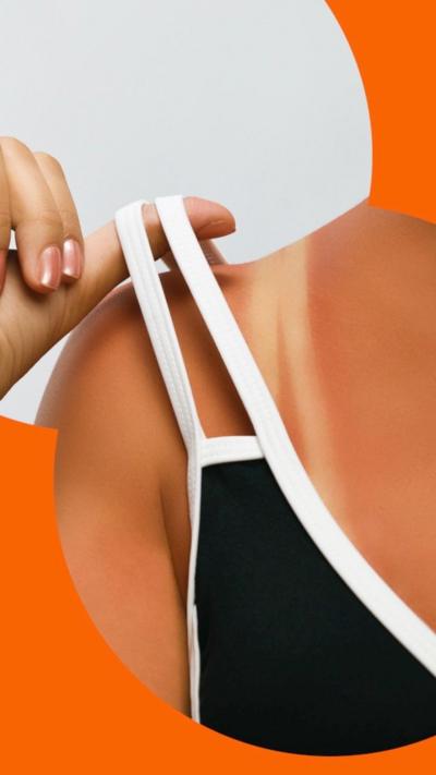 A close up of a woman holding the strap of her bikini off her shoulder to reveal a tan line.