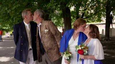 Two same-sex couples kissing