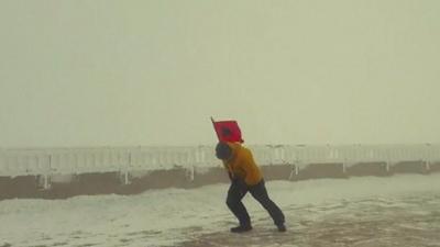 Man carrying flag in high winds